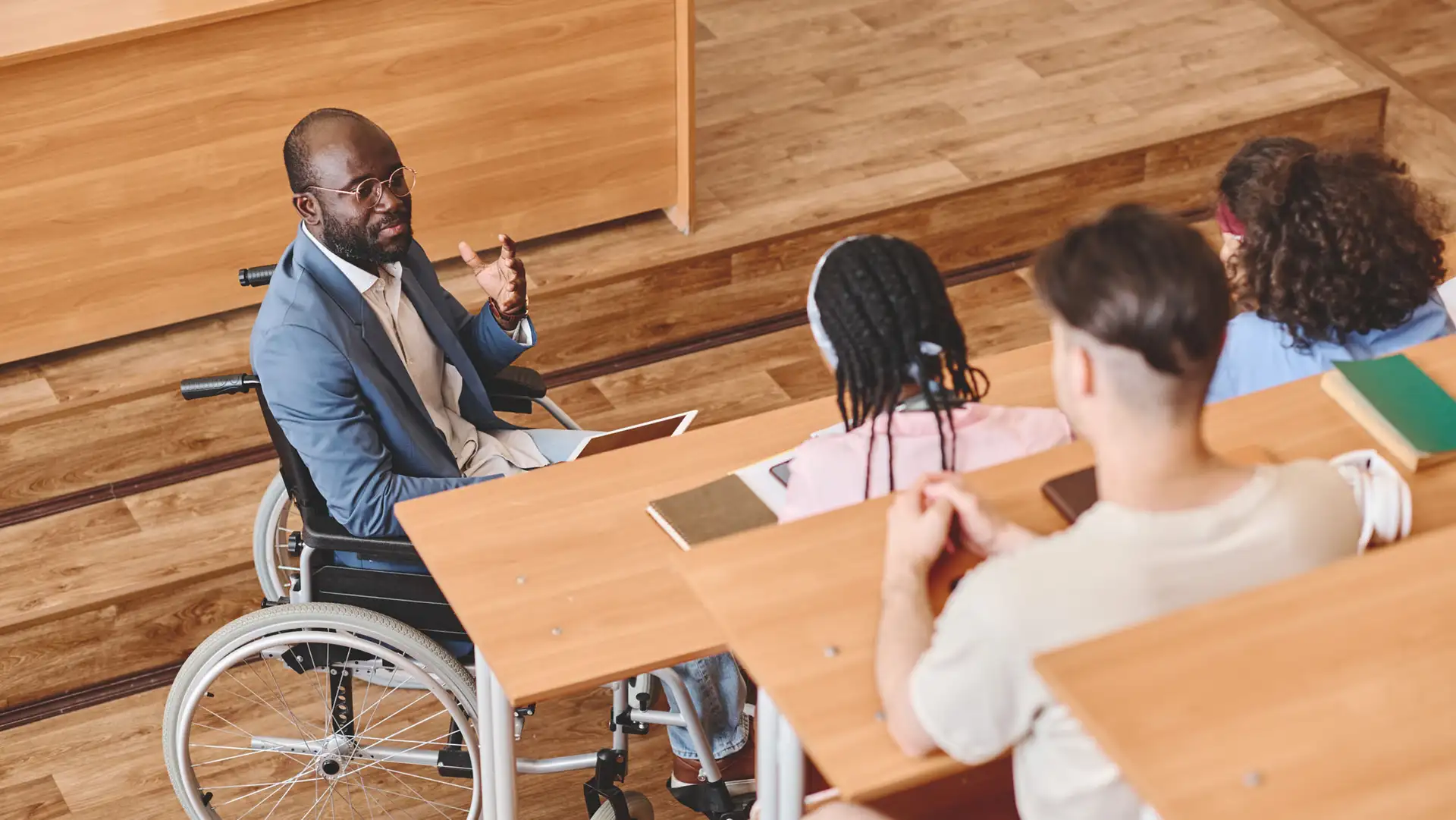 A teacher using a wheelchair with students seated at desks