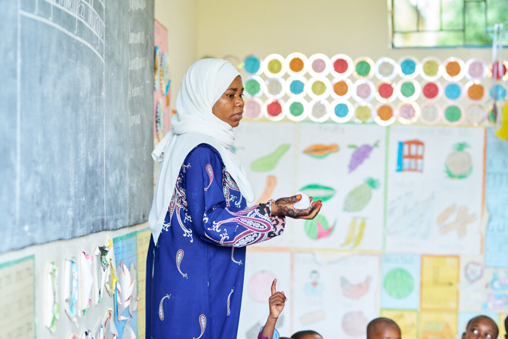 A teacher in Tanzania stands before her class.