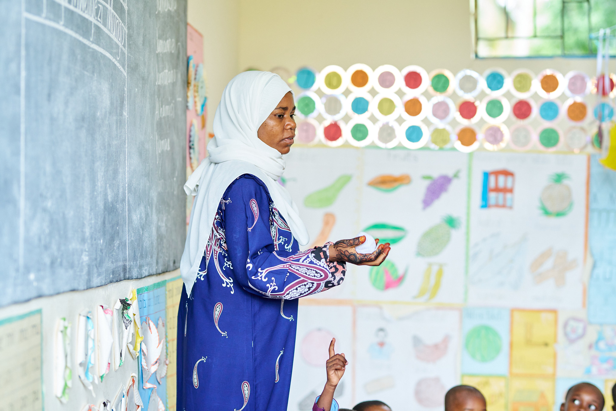A teacher in Tanzania stands before her class.
